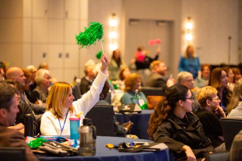 people at a conference raising pom poms